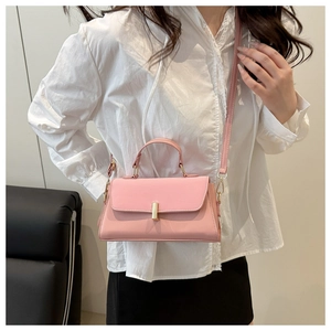 Close-up of pink leather handbag featuring gold cylindrical metal lock and top handle