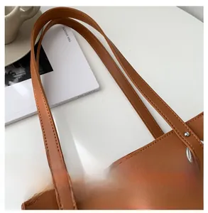 Detail of brown PU leather tote bag handle with silver metal ring and stitching