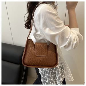 Détail de la texture en cuir tressé marron sur un sac porté épaule au style français épuré