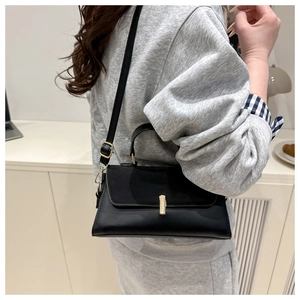 Close-up of black crossbody bag featuring a golden rectangular clasp on matte leather