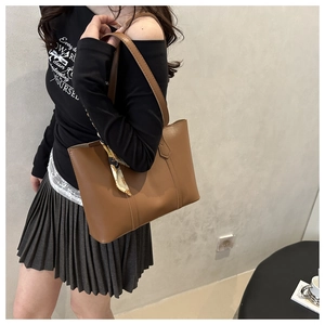 Side view of a large brown leather tote bag with decorative floral scarf on a model