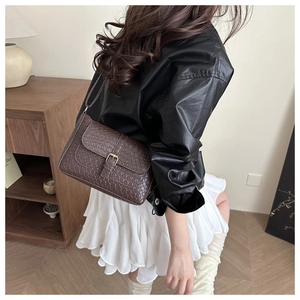 Detail of dark brown woven texture shoulder bag with retro gold buckle on flap