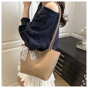 Detail einer Tragetasche mit weißer Spitzenschleife und goldener Fashion Bag Logo-Prägung