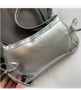 Detail der silbernen Crescent-Bag mit Metallfalten, Schleife und Punk-Nietenbesatz
