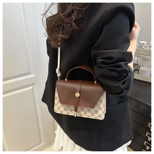 Detail of vintage bicolor handbag showing brown flap and beige patterned body with strap