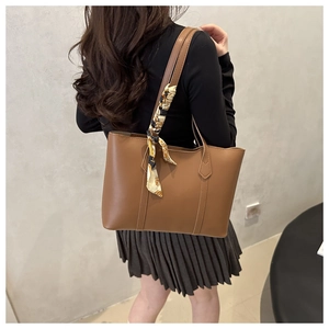 Brown tote bag with printed silk scarf detail shown on a model from a side perspective
