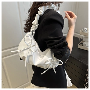 Detail view of white shoulder bag with bow accents and ruffled pleated strap style