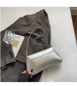 Macro detail of silver baguette bag showing smooth metallic finish on grey blazer