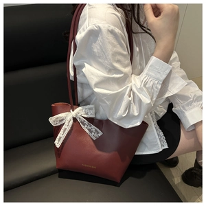 Details der burgunderfarbenen Tote-Bag mit weißer Spitzenschleife und Gold-Schrift