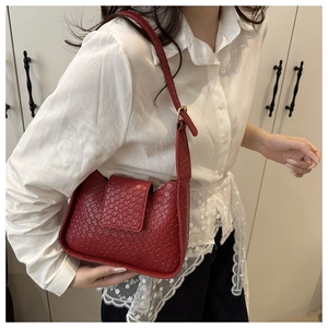 Détail du sac bandoulière rouge à texture tressée, finition cuir et boucle métallique