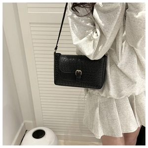 Close-up of black woven leather shoulder bag with a stylish gold buckle clasp and flap