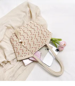 Detail of woven straw tote bag with brown polka dots and a wooden bead tassel charm