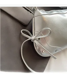 Details der silbernen Y2K-Tasche mit Faltenstruktur, Schleife und Metallnieten