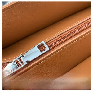 Detail of smooth silver metal zipper and fine stitching on the brown leather tote bag