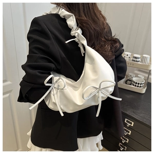 Detail of white PU cloud bag featuring ruffled shoulder straps and elegant bow accents