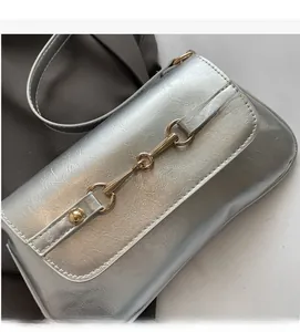 Detail of silver shoulder bag showing metallic texture and golden horsebit buckle hardware