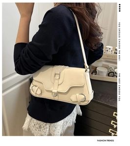 Détail du sac bandoulière en cuir crème avec boucle argentée et design de bandoulière