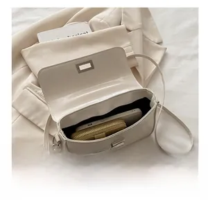 Vue intérieure du sac bandoulière blanc cassé montrant l'espace pour téléphone et portefeuille