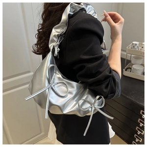 Close-up of metallic silver cloud bag with bow details and pleated strap on model