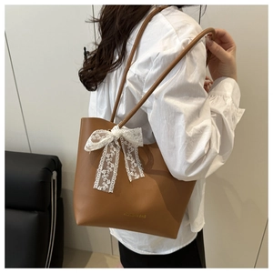 Détail du cabas marron caramel avec nœud en dentelle florale blanche sur la bandoulière