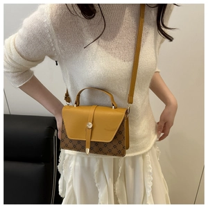 Detail of retro color-block handbag showing brown patterned body and yellow leather flap