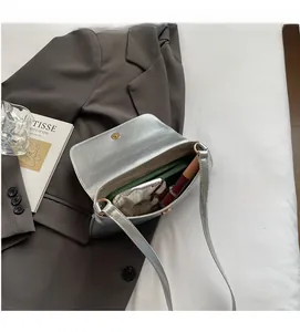 Silver metallic crossbody bag showing internal capacity with phone and cosmetics inside