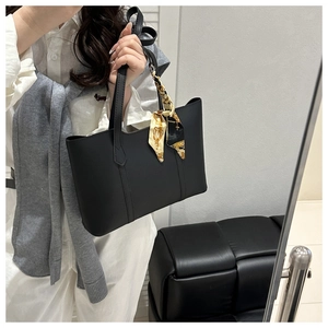 Close-up of black tote bag with matte finish and decorative printed silk scarf on handle