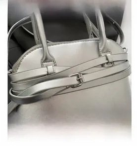 Close-up of silver textured leather handbag with stylish strap and metal eyelet details