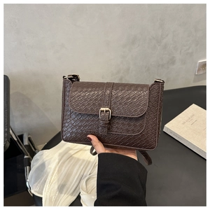 Détail du sac à main marron foncé avec texture tressée et boucle en métal doré élégante
