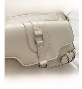 Détail de la boucle en métal argenté et coutures précises sur le sac en cuir PU beige