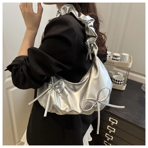 Detail of silver crescent bag featuring double bows and ruffled pleated shoulder strap
