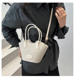 Detail of cream woven bucket bag with leather patch on white staircase background