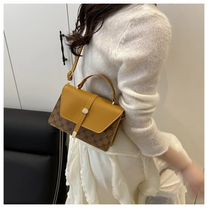 Close-up of vintage yellow flap bag with brown floral pattern worn on the shoulder