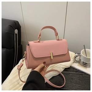 Close-up of minimalist dusty rose handbag featuring a gold cylindrical metal lock buckle