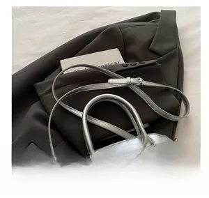 Detailed view of silver textured crossbody bag with adjustable strap on brown blazer