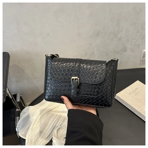 Détail de la texture croco noire et de la boucle dorée sur ce sac à bandoulière chic