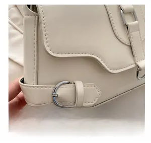 Détail de sac en cuir PU blanc cassé avec boucle en métal argenté et coutures soignées