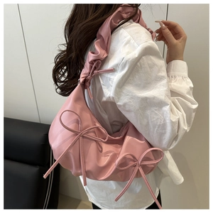 Close-up of pink shoulder bag with bow details and ruffled strap on female model