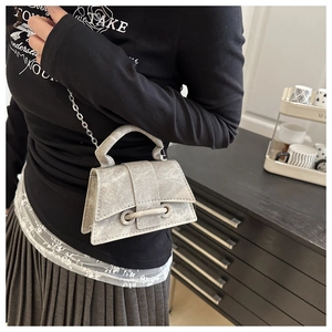 Detail of silver-grey mini bag with matte texture, chain strap, and top handle