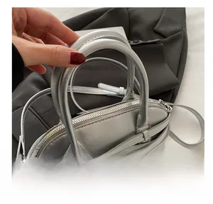 Detail view of the silver leather shell bag showing the zipper and twin handles