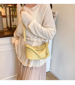 Detail view of a pale yellow lychee pattern leather handbag with gold twist lock and strap