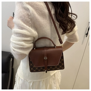 Detail of a brown crossbody bag featuring quilted patterns and a round metal lock clasp
