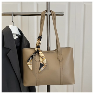 Detail view of khaki tote bag with colorful silk scarf on a metal display stand
