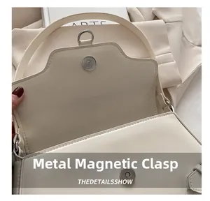 Détail macro du fermoir magnétique et des surpiqûres sur un sac à main en cuir crème