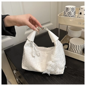 Détail du sac à main blanc avec broderie florale en dentelle et breloques papillon en 3D
