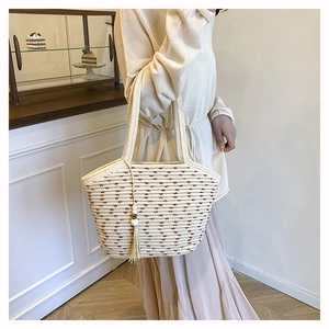 Close-up of contrast woven straw tote bag with beaded tassel and wave patterns