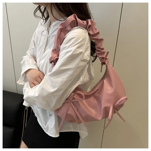 Detail of pink pleated strap shoulder bag with bow accents on soft faux leather finish