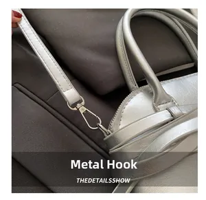 Macro detail of silver handbag with metallic texture, chrome lobster clasp and strap hooks