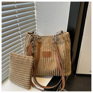 Close-up of corduroy tote bag set with chain detail and leather straps in khaki