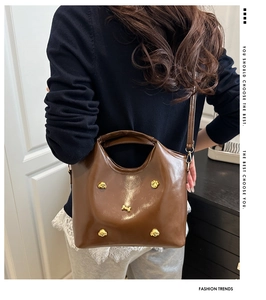 Detail of dark brown glossy PU leather tote bag with unique golden dog rivets